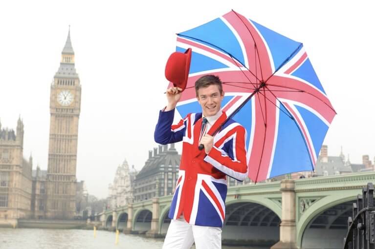 Homem vestido com casaco e guarda-chuva da bandeira do Reino Unido.