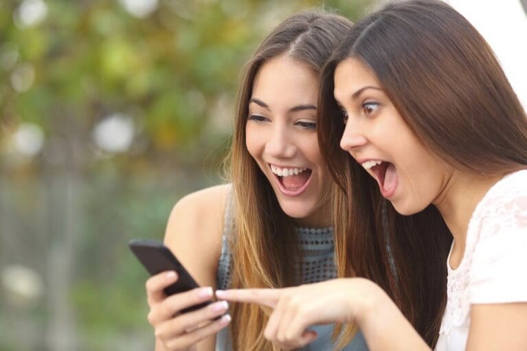 Duas jovens entusiasmadas a olhar para o smartphone